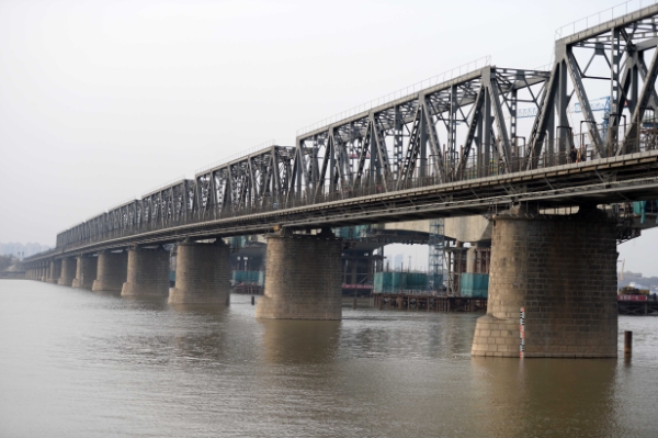 新华社照片，哈尔滨，2014年4月20日
    百岁松花江最早江桥退役
    这是哈尔滨滨洲铁路桥（4月19日摄）。
    日前，被哈尔滨人亲切地称为“老江桥”的松花江滨洲铁路大桥正式暂停使用。不少市民和游客登上这座桥，与这座百年历史的“钢铁巨人”合影留念。
    滨洲铁路桥又称哈尔滨中东铁路桥，1900年5月16日正式动工，1901年8月22日全面完工，同年10月2日交付使用，是松花江上最早的铁路大桥，也是哈尔滨的第一座跨江桥梁。该桥由沙俄时代桥梁专家、中东铁路工程局桥梁总工程师连多夫斯基亲自监督，工程师阿列克谢罗夫负责施工。全长949米，桥墩用花岗岩砌筑，十分坚固。1962年7月，由东北铁路工程局设计并进行了该桥梁的加固。
    据了解，滨洲铁路桥已于2008年纳入第三次全国文物普查范围，是不可移动文物，将作为文物完整保留，成为哈尔滨旅游观光桥。
    新华社记者王凯摄