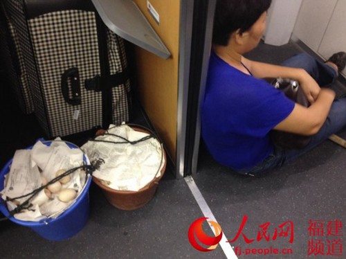 怕碰坏给孩子补充营养的蛋，她把两个桶移到车厢，自己坐在过道旁的地上。林长生 摄