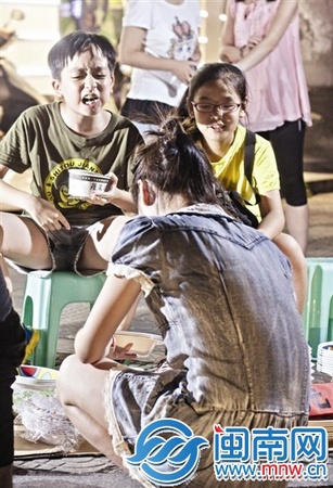 边吃臭豆腐边和客人推介的孩子，一脸认真