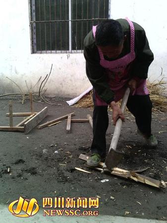 老汉正在埋头将课桌劈来当柴烧