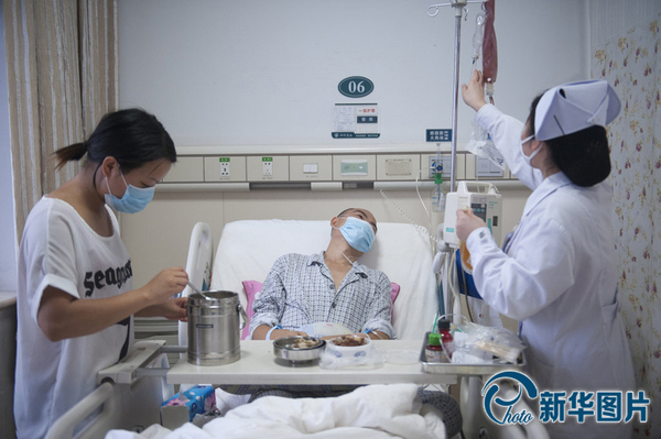 李真病床旁，向华与护士各站一边，向华把饭菜摆上小桌，护士换药瓶，李真靠在床上看着护士换药瓶，没有看他平时最爱吃的香干炒肉。