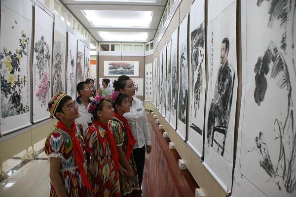 援疆捐赠暨书画创作展等系列文化公益活动在乌市举行。5图为少数民族学生认真观看书画展览