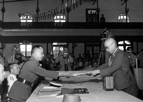 中国战区的日本投降仪式上，日本中国派遣军总司令官冈村宁次在对华投降书上签字，并向中方交出他的随身佩刀，以表示侵华日军正式向中国缴械投降。这是何应钦(左)在南京代表中国政府接受侵华日军总司令冈村宁次的投降书。