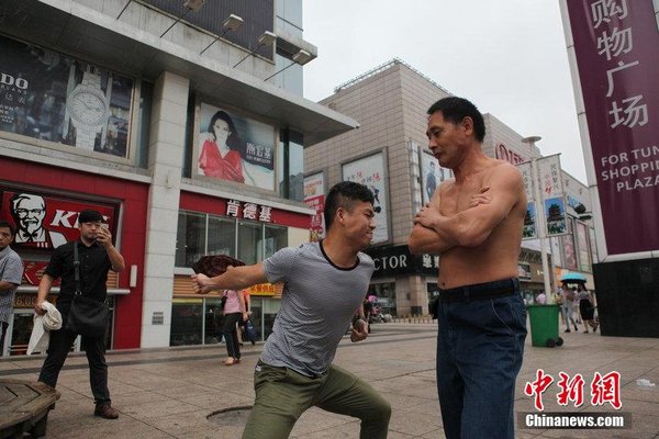 2014年08月18日，江西省南昌市，没有健硕的肌肉，却特别能承受拳力，48岁的湖北孝感男子谢水平不仅走遍全国各地向人发出挑战，甚至还把挨打当成了职业。昨天上午，谢水平来到八一广场说，三拳之内，能将他击退、双脚退到线后，就算挑战成功，单脚后退则是平局。