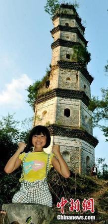图为8月25日，“无腿女孩”蒋张子怡在半边古塔前，手握双拳，开心表示自己和塔一定会坚挺下去。卓忠伟 摄