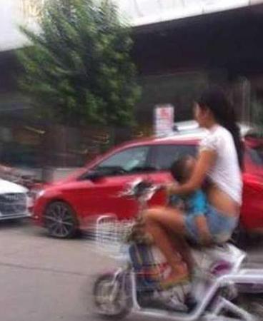妈妈边骑车边给孩子喂奶。