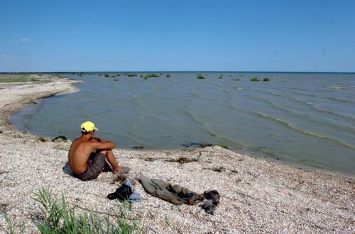 该地区的气候也随着咸海干旱发生着剧烈变化。咸海水量减少，对当地气候的影响也变弱，周边地区冬天的气温越来越低，夏天的气温则越来越高。图为当地居民坐在咸海边。