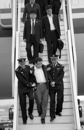 5月9日，在北京首都国际机场，李华波（前中）被押解下飞机。新华社发