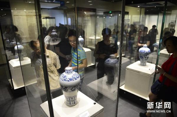 观众在观赏一组六个青花云龙纹缠枝牡丹纹带盖梅瓶