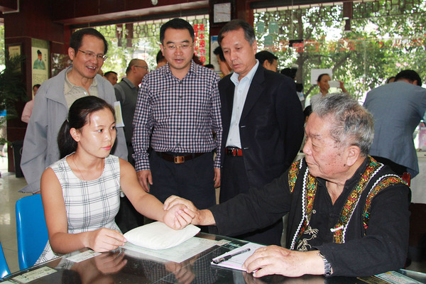 83岁的贵州老苗医熊文美给患者号脉，黄元河、陆洪光、安阿玥（从左至右）驻足了解。