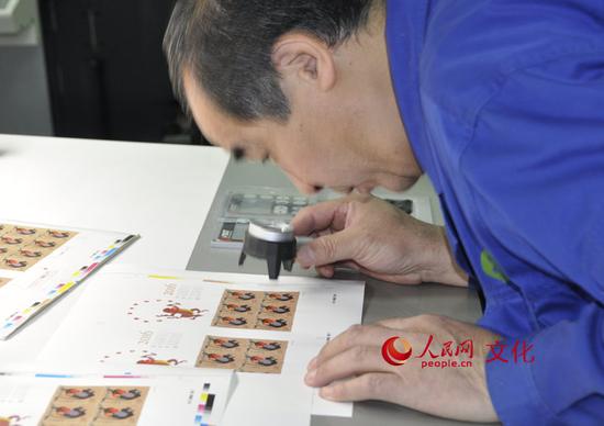 印刷车间里的工作人员正在用放大镜检查印刷效果。（人民网 王鹤瑾 摄）