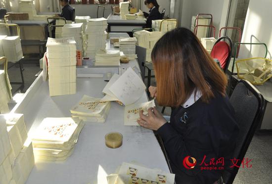 检票员正在仔细检查每一张邮票。（人民网 王鹤瑾 摄）