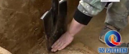 考古专家用铲子去除桦木条表面的沙土。