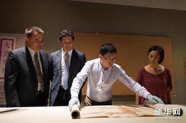 12月8日，在位于澳大利亚堪培拉的澳大利亚国家图书馆展厅，来自中国国家图书馆古籍部文献修复组的朱振彬（右二）展开《大清门至坤宁宫中一路立样糙底》。