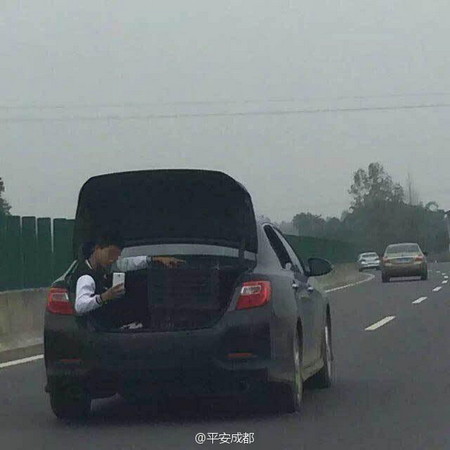 小伙坐后备箱悠闲玩手机