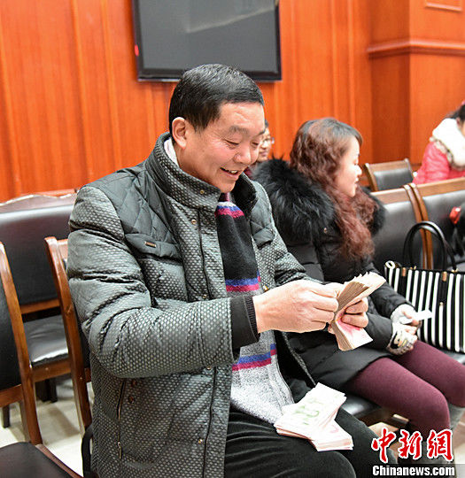 图为农民工清点自己领到的钱。中新社记者