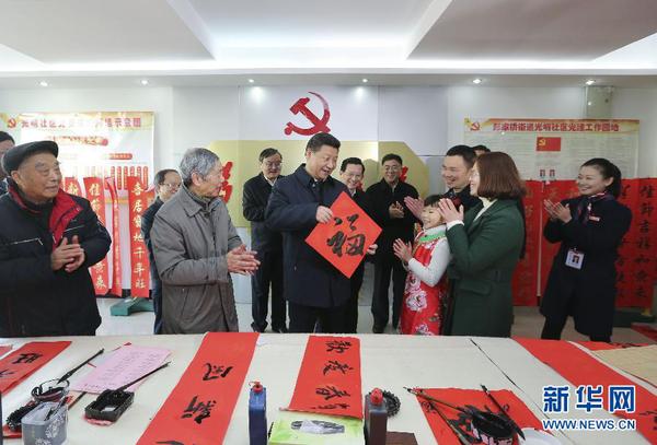 这是2月3日，习近平在南昌市东湖区彭家桥街道光明社区书画室，接过一位小朋友现场书写的 “?！弊郑４蠹叶夹腋?。 新华社记者兰红光摄