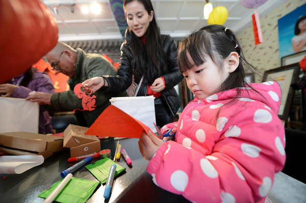 2A 小朋友在妈妈的陪同下剪纸做灯笼。