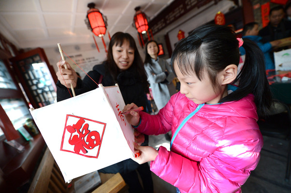 14A图为孩子们在家长的陪同下扎灯笼，描画图案。