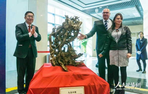 中国侨联副主席乔卫（左）与捐赠人夫妇为九龙木雕揭幕