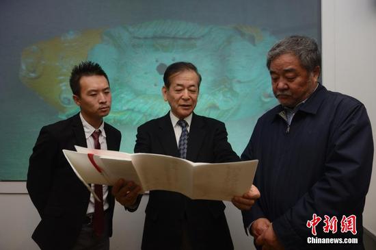 　　3月28日，牟田口章人（图中）向内蒙古博物院院长（图右）介绍捐赠的文献。当日，日本帝塚山大学文化创造学科教授牟田口章人在呼和浩特，向内蒙古博物院捐赠了辽代文物“双鱼形琉璃釉建筑构件”。据悉，该文物是他在日本自己出资购得，同时他还代友人捐助了辽代历史研究文献。中新社记者 刘文华 摄