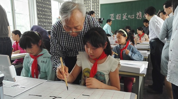 政协委员“手把手”给孩子们进行书法指导。