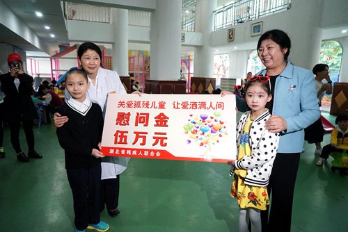 图为省残工委副主任、省残联党组书记、理事长陶慧芬委武汉市儿童福利院孤残儿童送去慰问金