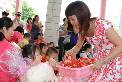 图为茂名市福彩中心主任程玉颜为福利院小朋友们派发糖果