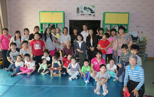 　图为张海迪主席在调研时与残疾儿童、家长合影