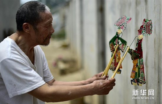 6月5日，张奎老人在屋外的墙上耍皮影