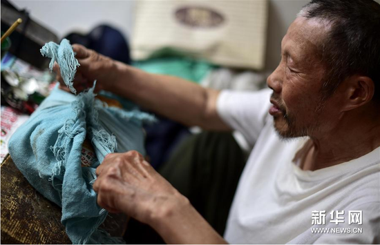 6月5日，张奎老人将雕刻皮影的纸模板紧紧地捆在包裹里