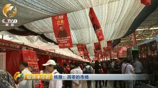 潘家园旧货市场的这块空地上，临时支起了一些棚子和摊位，正在举办一个核雕展销会。顶棚上方高高悬挂着前来参加展销会的雕刻师的照片。