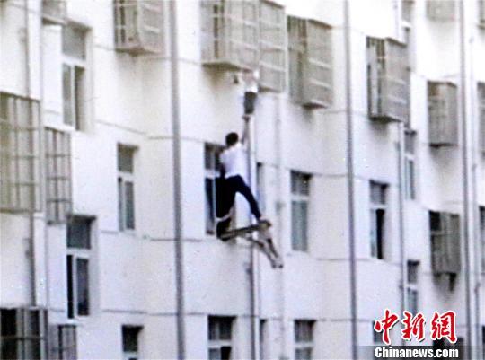 几名业主固定板凳，一名业主站上板凳托举男孩双脚 宋俊初 摄