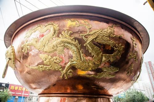 据介绍，这个火锅是按照真实火锅的尺寸等比例放大制作的，高5.55米，直径5.35米，总重量3.3吨，耗时两个多月量身订制，通体铜质，花费40余万人民币。