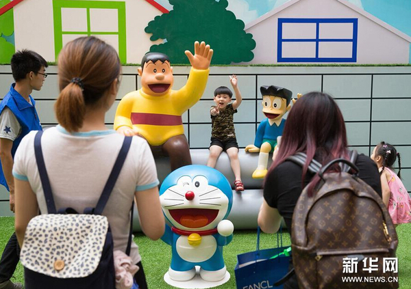 7月31日，一名小朋友在展出的卡通造型旁拍照。