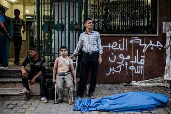 　　“他的父亲去世了，而他还不了解这意味着什么”。 12岁的艾哈迈德（Ahmed）和他的叔叔在他父亲的尸体旁等待，他的父亲被飞向阿勒波（叙利亚）的炮弹袭中，艾哈迈德的后背也被弹片划伤了。 摄影师：尼科尔·唐