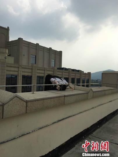 图为“盘踞”无锡某商场楼顶多日的长发人体模型?！∏蒯?摄