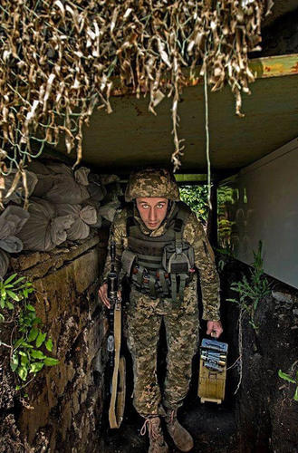 分别手持AK步枪和弹药箱的乌政府军士兵在掩体中留影。