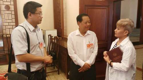 全国政协副主席刘晓峰（中）了解报道情况