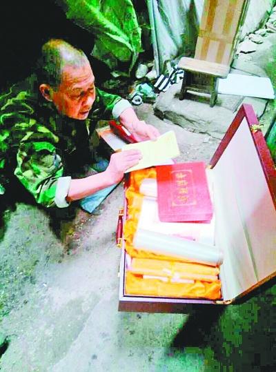 　代爹爹展示收到的“纪念章”和“十大名画”。