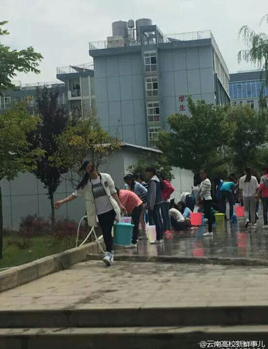 图为学生排队提水。