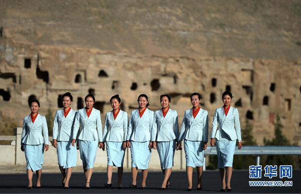 身着全新工作制服的莫高窟讲解员从洞窟前走过。新颖别致的服装既方便了游客识别工作人员，也成为景区内一道靓丽的风景。新华社记者陈斌 摄 图片来源：新华网