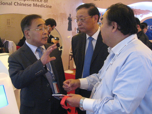 二、王国强（中）与中国中医科学院院长、中国工程院院士张伯礼（左一）在第九届全球健康促进大会中医药体验展馆尚力博士的导引下参观。 人民政协网记者 张春莉 摄影