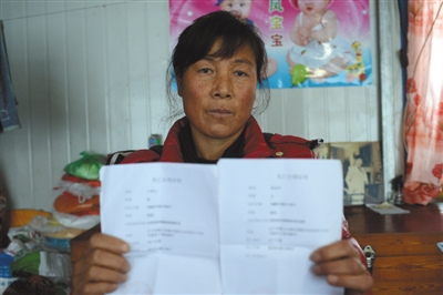 12月13日下午，杨福珍手捧着大儿子和儿媳妇的死亡证明。2012年8月4日凌晨，暴雨导致的泥石流袭击了岫岩县南马峪村。杨福珍失去了丈夫、大儿子和大儿媳。