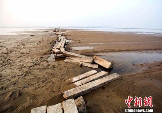 　　近年来，当鄱阳湖水位下降至枯水位时，石桥就会露出水面，成为当地一景。图为游人在古桥上行走。12月23日摄　傅建斌　摄