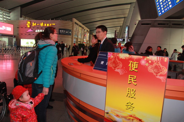 北京南站一位母亲带着孩子咨询高铁列车信息  摄影 李木元