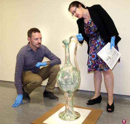 　　代表纽约亚洲学会的普罗瑟博士（右）正在检验即将装箱运往美国的唐代白釉绿彩高足把壶和绿釉龙首榫。左为亚洲文明博物馆的史蒂芬·墨菲博士。（新加坡《联合早报》/周柏荣 摄）