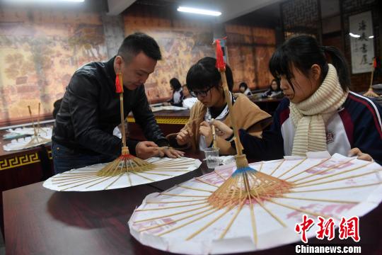 课堂上，严磊手把手地教导学生如何制作油纸伞?！÷烂?摄