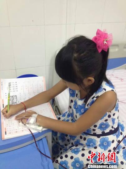 图为珊珊在医院一边输血一边写作业。 家属供图