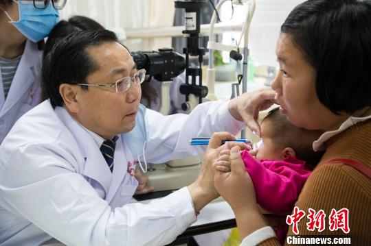 亢泽峰(左)为幼儿义诊。　李南轩 摄